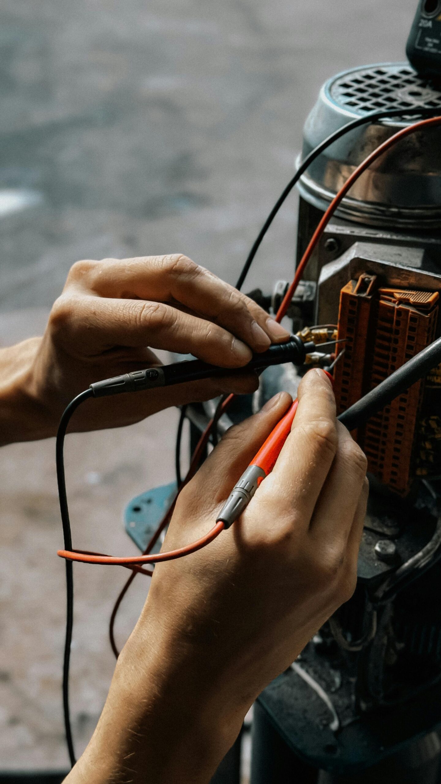 Close-up of hands using multimeter on motor wires. Precision in electrical testing.